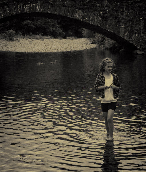 Girl in river near bridge,Cumbria
