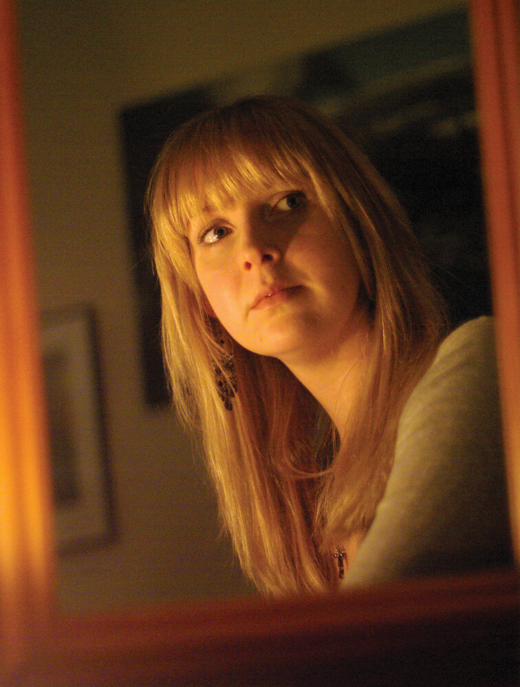 Andrea in the mirror by candlelight. FA 50mm f/1.4 at f/1.4 and ISO1600.