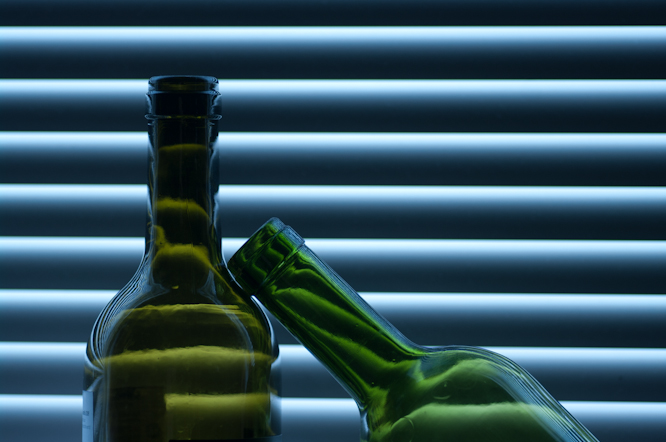 Wine bottles against a window blind on fluorescent setting